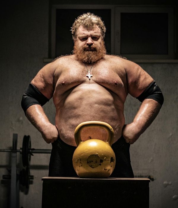 Man performing a controlled strength exercise with a kettlebell in a minimalist gym.